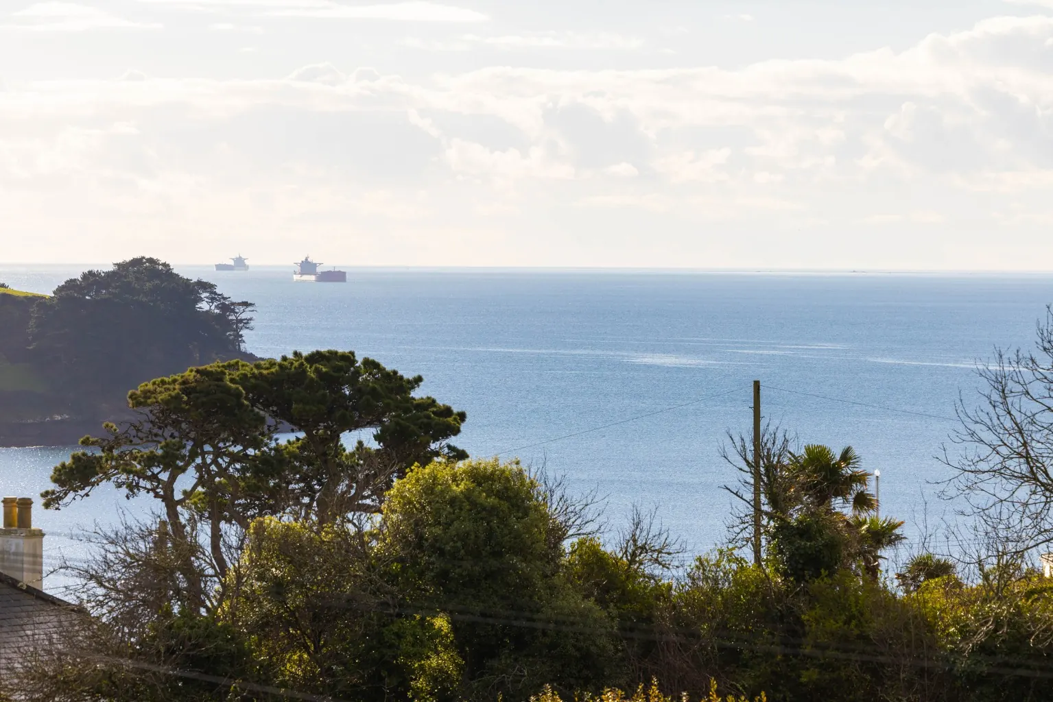View across Carrick Roads towards the headland and open sea, with shipping at anchor