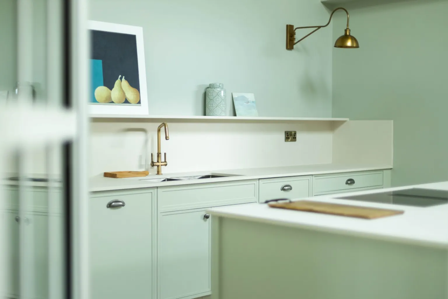 Bespoke kitchen in pale green with brass tap and wall light