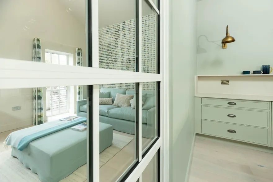 Fitted painted joinery with brass handles and a brass wall light in the main bedroom