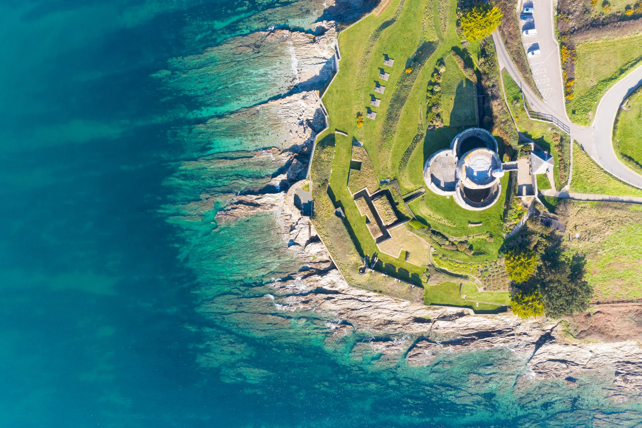 Aerial view of a coastal headland and gun battery beside turquoise water