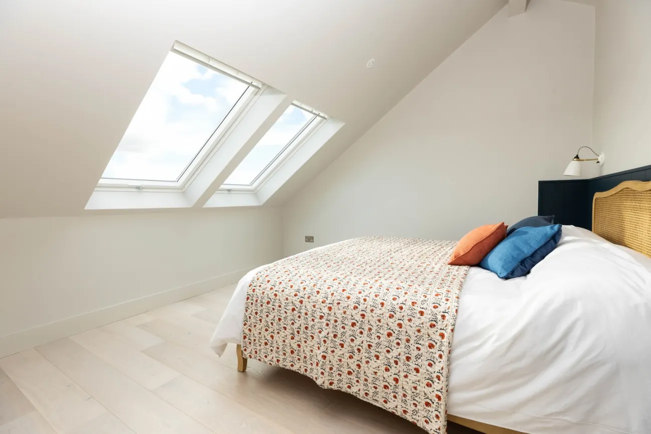 Roof lights set into the sloping ceiling of the main bedroom, above a bed with a block-printed throw