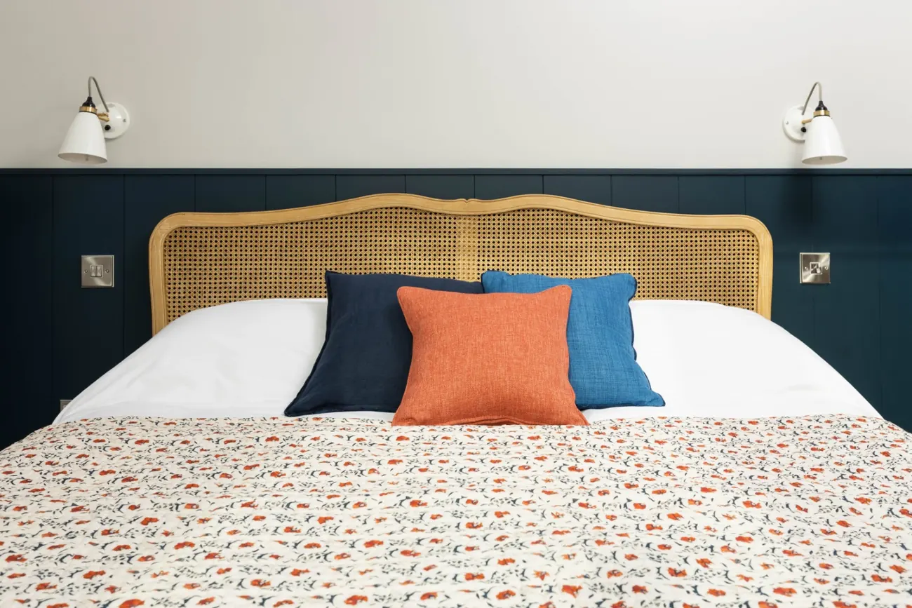 Main bedroom with blue panelling, caned headboard and coral cushions