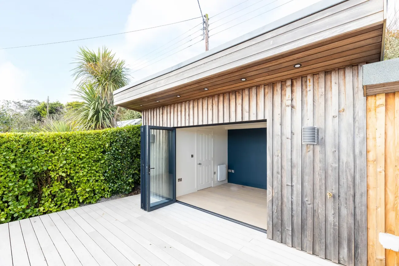 Larch-clad garden pavilion with bifold doors opening onto a deck